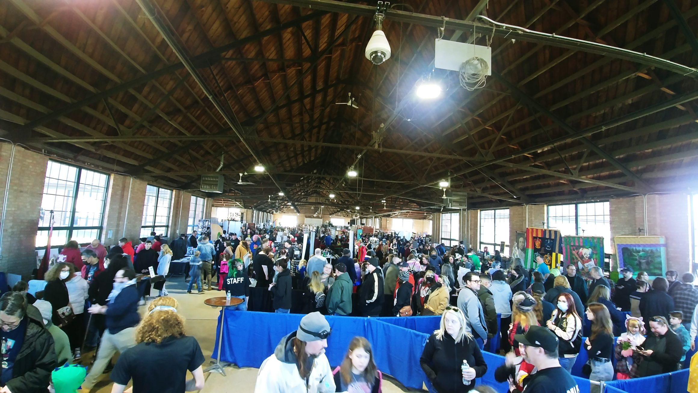 A photo of the entrance of the NWI Comic Con showing a large open venue packed with people.