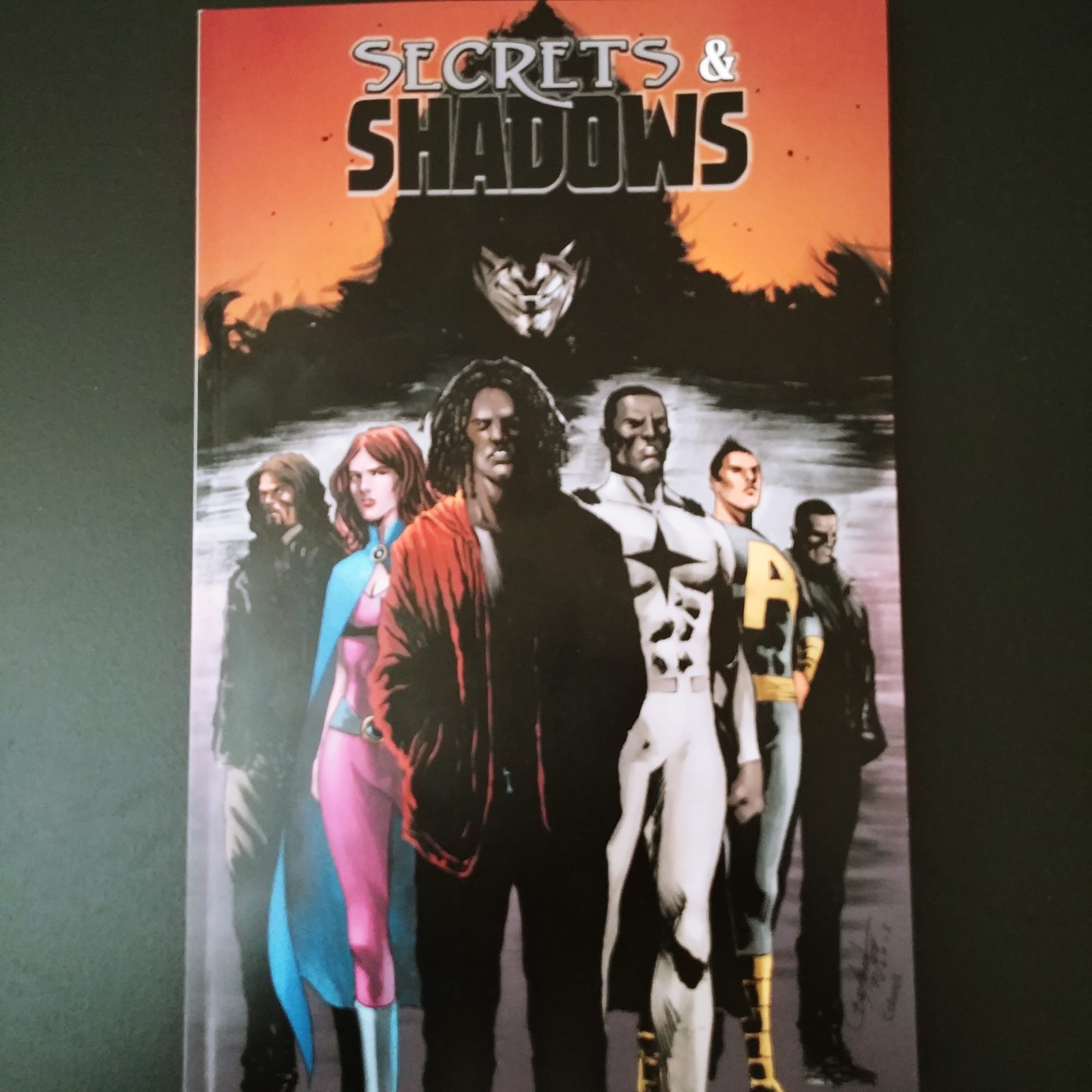 A picture of the first physical proof of the Secrets & Shadows TPB showing the villainous Shadow looming over the Joseph and the heroes.
